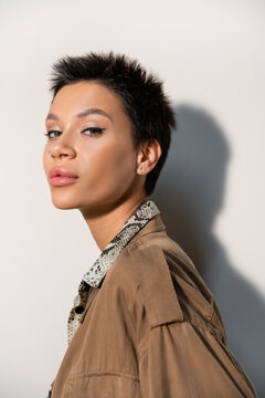 Portrait Of Brunette Archaeologist With Short Hair And Makeup Looking At Camera On Grey Background.