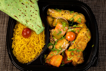 top view of an Egyptian meal consists of rice , chicken , salad , bread and vegetables