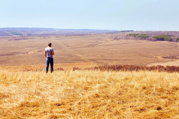 mature man stands on a hill and looks into the distance. spring sunny day