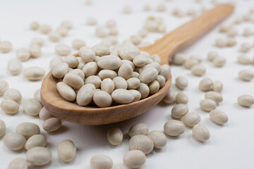 White beans in a wooden spoon on white background