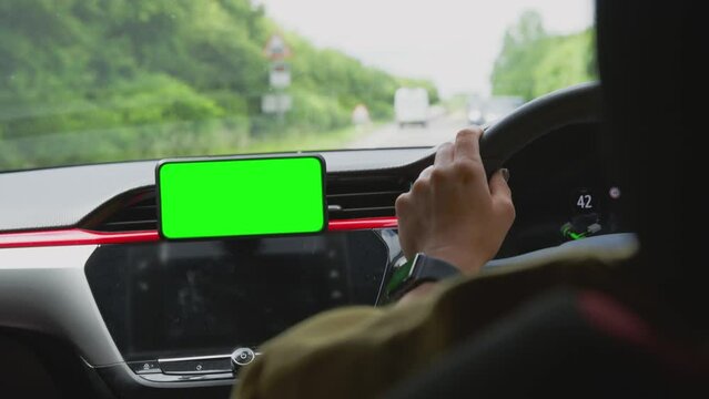 Close up of woman driving car with hands free unit for green screen mobile phone mounted on dashboard - shot in slow motion