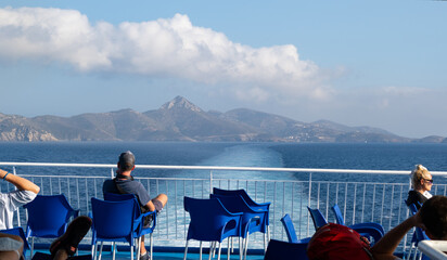 Tourists sitting on the deck of a ferry ship through the Aegean Sea from Samos