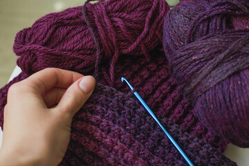 Hat or sweater crocheting process, dark wine acrylic yarn, and skeins with female hand. Crochet,...