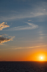 Naklejka premium Colorful orange sunset over the Aegean Sea next to the Greek island of Ikaria next to a building with colorful reflection