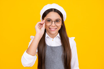 Tennager child girl wear eyeglasses looking at camera with confidence over yellow background, copy space. Kid get eyesight. Happy face, positive and smiling emotions of teenager girl.