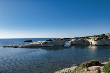 Majestic shot of Sarchittu beach and the Limestone rock with arch in the Sardinia