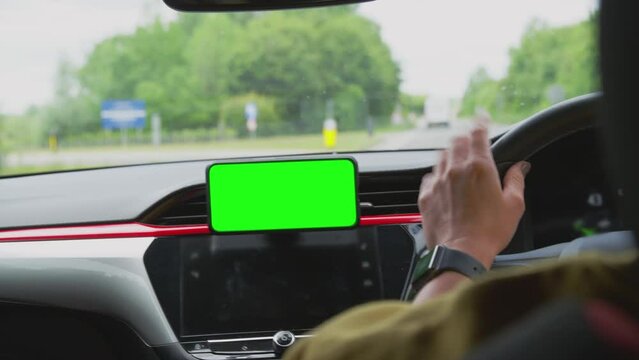 Close up of woman driving car with hands free unit for green screen mobile phone mounted on dashboard - shot in slow motion