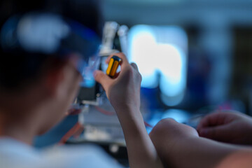 A cute boy constructs metal robot and program it boards microcontrollers on the table STEM education inscription. Programming Mathematics The science Technology DIY workshop at class in the classroom