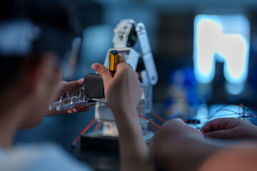 A cute boy constructs metal robot and program it boards microcontrollers on the table STEM education inscription. Programming Mathematics The science Technology DIY workshop at class in the classroom