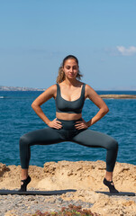 Fototapeta na wymiar Malia, Crete, Greece. 2022. Pilates exercises on the beach. The plie squat position.