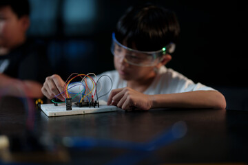 A cute boy constructs metal robot and program it boards microcontrollers on the table STEM education inscription. Programming Mathematics The science Technology DIY workshop at class in the classroom