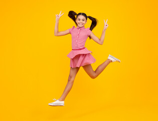 Excited face. Amazed expression, cheerful and glad. Full length little overjoyed teen girl 12, 13, 14 year old jump and run isolated on yellow background studio.