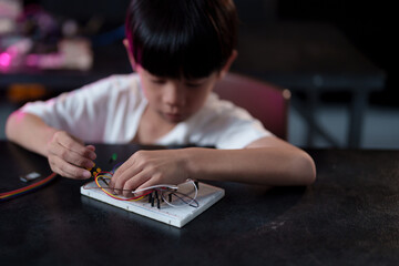 A cute boy constructs metal robot and program it boards microcontrollers on the table STEM education inscription. Programming Mathematics The science Technology DIY workshop at class in the classroom