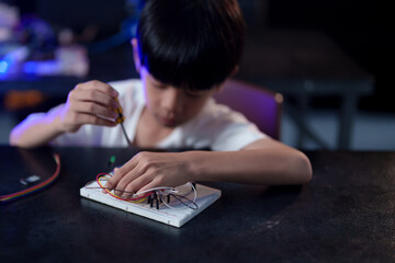 A cute boy constructs metal robot and program it boards microcontrollers on the table STEM education inscription. Programming Mathematics The science Technology DIY workshop at class in the classroom