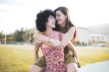 Two women carrying their friend on their backs. Lesbian women couple on the street. The woman is taking a piggyback ride with her girlfriend. lifestyle concept.