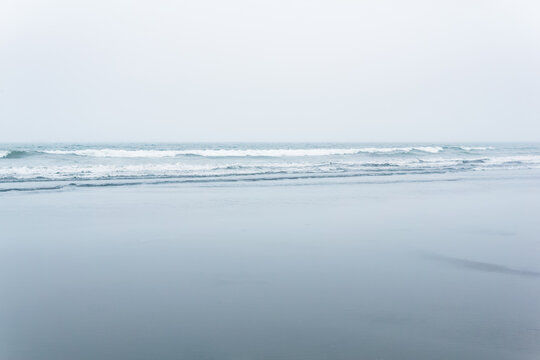 foggy seascape, cold ocean shore with a wide beach