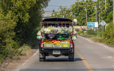 A car with a fresh fruit and vegetable shop is driving on the road, Thailand