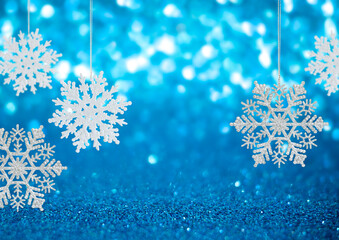 Snowflake hang on Winter holidays blue background with copy space