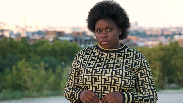Portrait of a young Equatoguinean woman looking at camera and laughing at street.