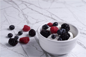 blueberries and raspberries with cream in the bowl