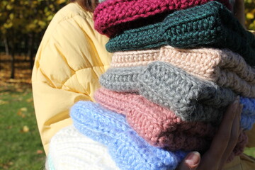 A lot of fashionable knitted hats in the hands of an unrecognizable young girl close-up. Fashion autumn-winter. Knitted voluminous hats. Autumn shooting. City Style. Knitting. Hobby. Handmade.