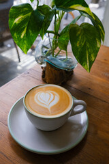 white cup of cappuccino on wooden background with beautiful latte art of heart shape