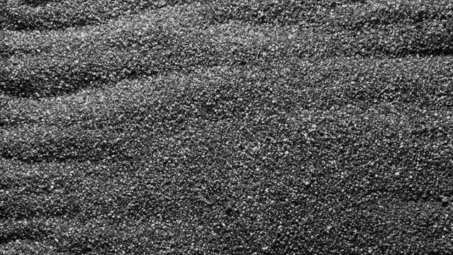 Black sand moving. Close-up of a black sand surface moving.