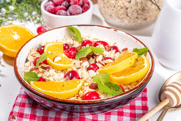 Christmas morning breakfast recipe, cranberry orange oatmeal. Cooked oats porridge with fruit and berry, on white table top view copy space