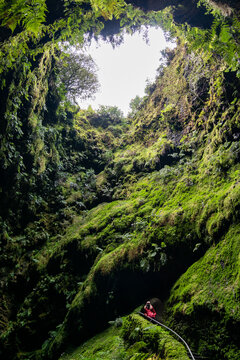 Cave in azores island. Mysterious cave with female looking up. Mystery cave entrence. Algar do Carv&atilde;o