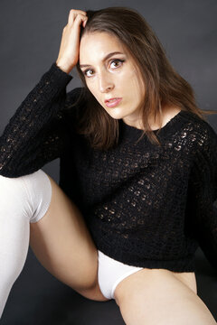 Young woman posing in black knit jumper and long white stockings in studio