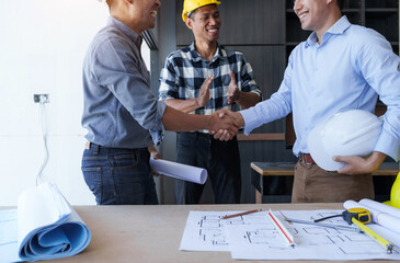 Shaking hands, Successful home renovation describes and examines newly built and renovated construction holding large house blueprints.