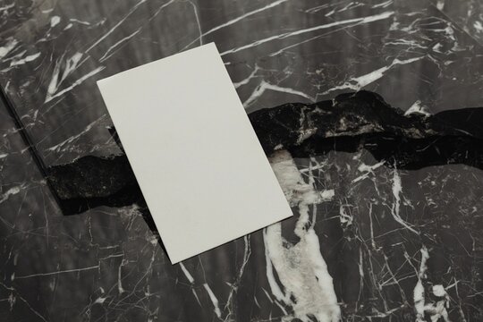 Top View Of A Black Marble Table Background With A White Blank Paper In The Middle