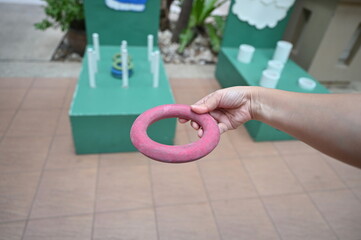 Hand holding a red rubber ring for throwing rings in throwing rings where players can throw green...