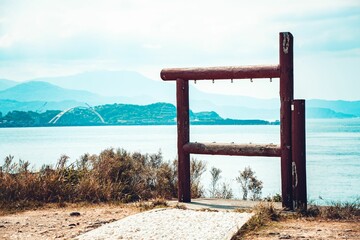 Wooden stand like thing placed on the shore of a sea on a background of mountains and forests