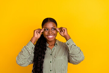 Photo of cute millennial brunette lady hands glasses look up wear striped blouse isolated on yellow color background