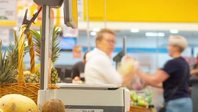 People weigh vegetables and fruits on scales in greengrocery department in supermarket, time lapse. 