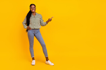 Fototapeta na wymiar Full body portrait of positive promoter girl indicate finger empty space isolated on yellow color background
