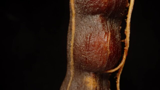 Peeled tamarind, extreme macro, zoom. Slow falling and moving away from the object. Isolated black background. Rotation.