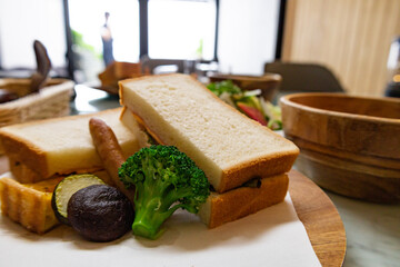 日差しが降り注ぐ爽やかなダイニングで前菜のグリーンサラダとサンドイッチの朝食のアップ（千葉県）