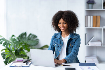 Attractive smiling African American businesswoman using laptop at office