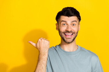 Fototapeta premium Portrait photo of young funky excited bristle beard man finger directing empty space offer unexpected good price sale isolated on bright yellow color background