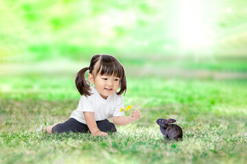 緑地で子ウサギと遊ぶ幼い女の子