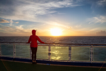 Fototapeta premium Adventure woman traveler enjoying colorful sunset from a Cruise Ship. North Atlantic Ocean. Travel Concept