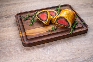 Beef Wellington meat baked in dough on a wooden board.