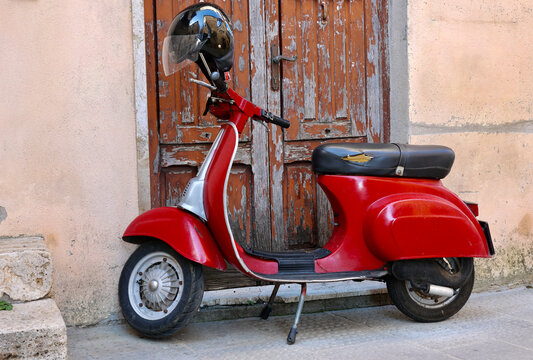 Typical street scene in Italy with a red scooter on an old narrow street. 