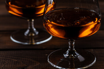 Two glasses of cognac are on a wooden table