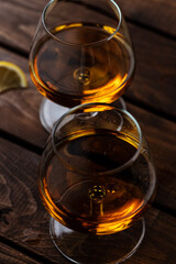 Two glasses of cognac are on a wooden table
