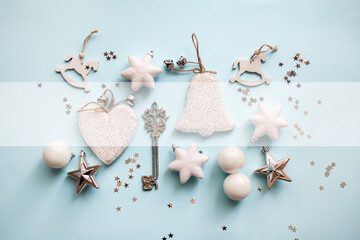 Christmas or New Year's flat lay composition of various decorative elements, sparkles and Christmas decorations in white and silver colors on a pastel light blue background. top view. copy space.