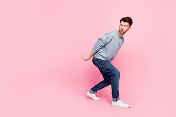 Full body photo of nice young man hold heavy box look suspicious empty space wear stylish blue clothes isolated on pink color background