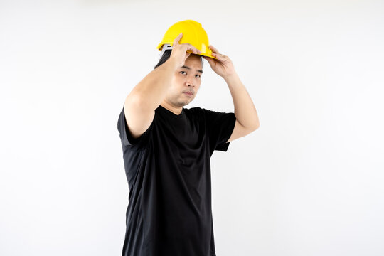Asian man is pretending to wear a yellow safety helmet and wear black t-shirt isolated on white background.